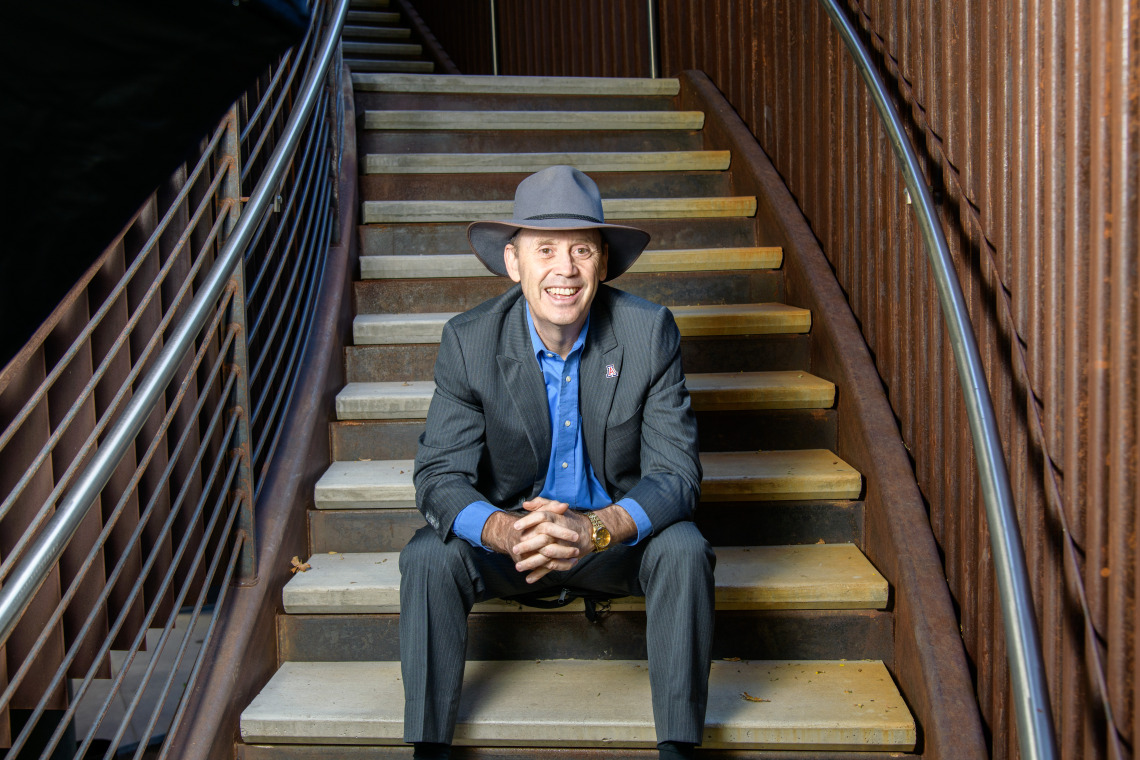 Dean Shane Burgess sits at the bottom of a metal staircase in the ENR2 building on the University of Arizona main campus